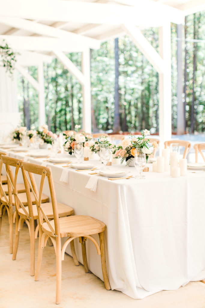 Peach wedding flower centerpieces, white linens, and crossback chairs