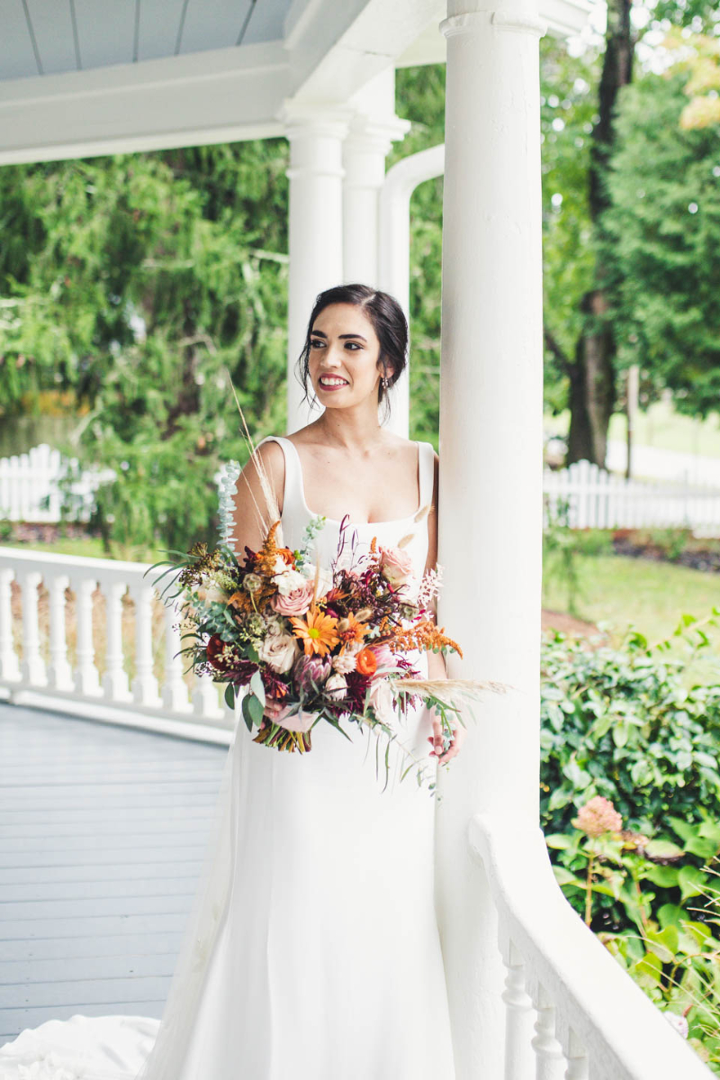 bride stands with fall bridal bouquet